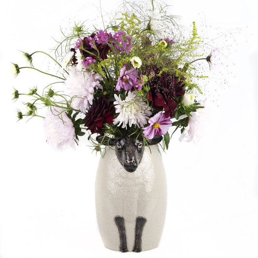 The QUAIL CERAMICS - BLACK SUFFOLK SHEEP VASE by QUAIL DESIGNS is a hand-painted ceramic vase with a textured white body and detailed black face and legs, featuring a calm expression for a whimsical, artistic touch.