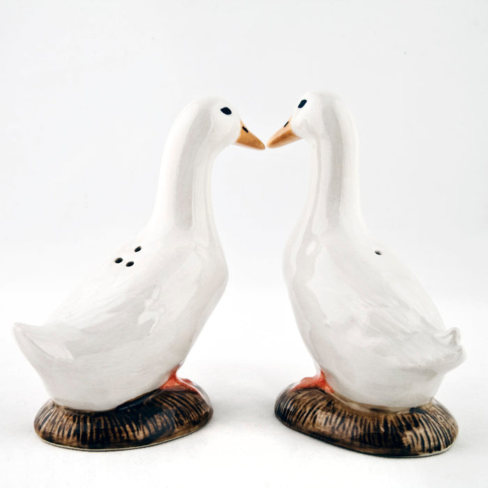 The QUAIL CERAMICS - PEKIN DUCK SALT AND PEPPER SET by QUAIL DESIGNS features two hand-painted stoneware duck figurines with white bodies and orange beaks, standing side by side on brown bases against a plain white background.