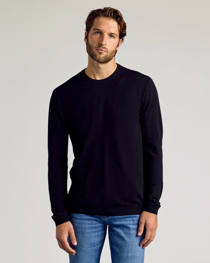 Man in Black Crew Neck Sweater 2-Pack, jeans, relaxed pose.