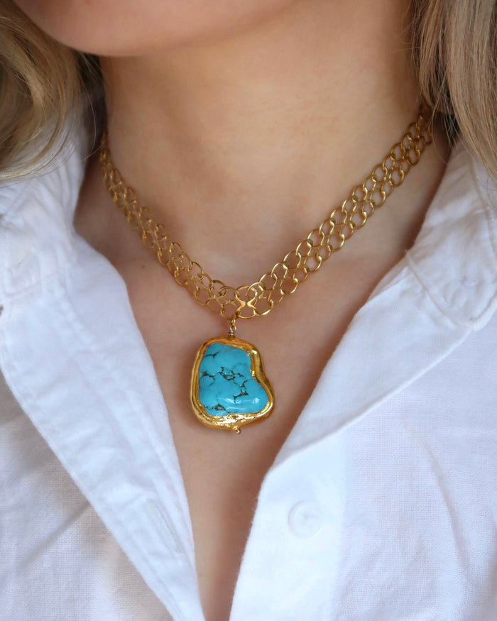 Woman wearing a gold chain necklace with a large turquoise pendant made in Greece, Greek jewelry statement necklace