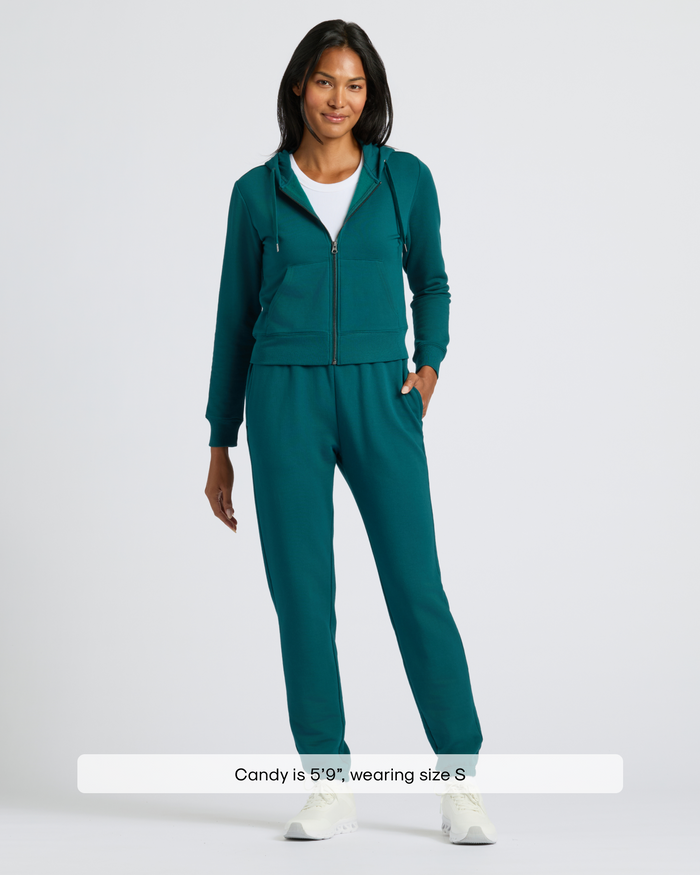 Woman in Womens Deep Emerald Relaxed Joggers, white T-shirt, teal hoodie.