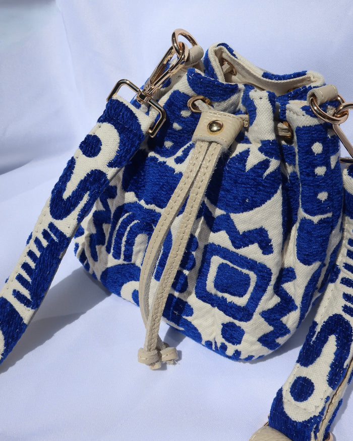 Cream and royal blue bucket bag with geometric shapes and a leather drawstring with an adjusble crossbody strap made in Greece