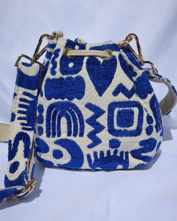 Cream and royal blue bucket bag with geometric shapes and a leather drawstring with an adjusble crossbody strap made in Greece. Rainbows, eyes, moons, heart print
