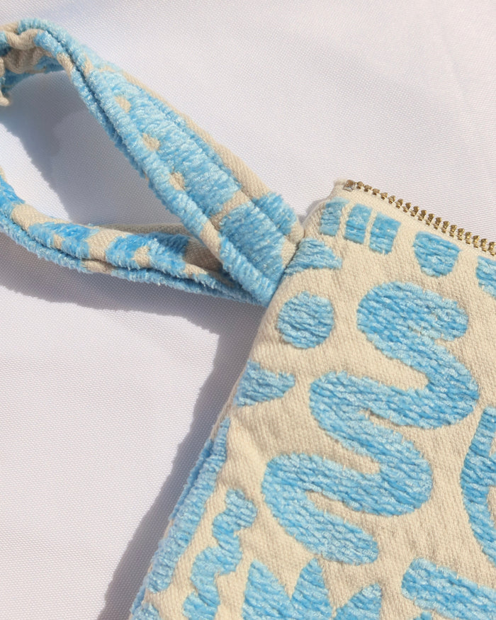 Wrist strap of woven cotton clutch bag wristlet with turquoise geometric print featuring evil eyes, rainbows, snakes, moons, and more made in Greece. Greek fashion accessory zipper pouch with tassel w